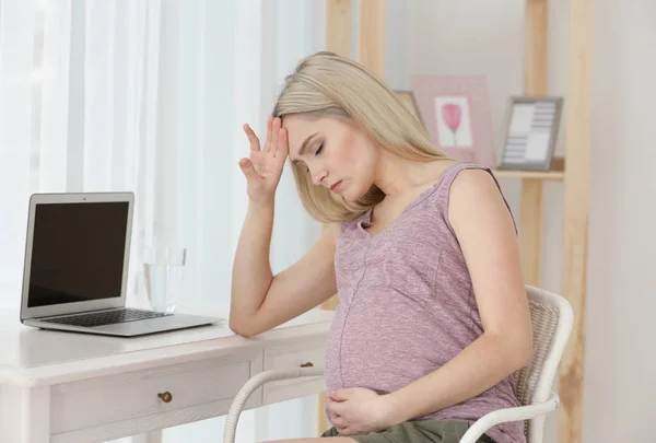 Молодая беременная женщина страдает от головной боли дома — стоковое фото