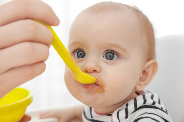 Father feeding cute baby daughter at home