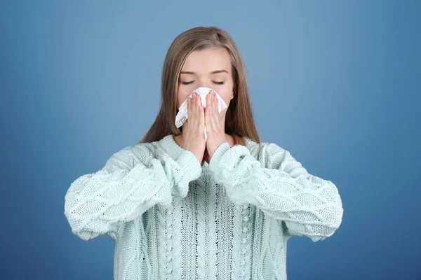 Junge Frau pustet Nase auf Gewebe vor farbigem Hintergrund — Stockfoto