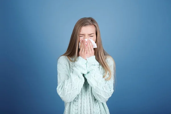 Młoda kobieta dmuchanie nosa na tkanki przed kolor tła — Zdjęcie stockowe