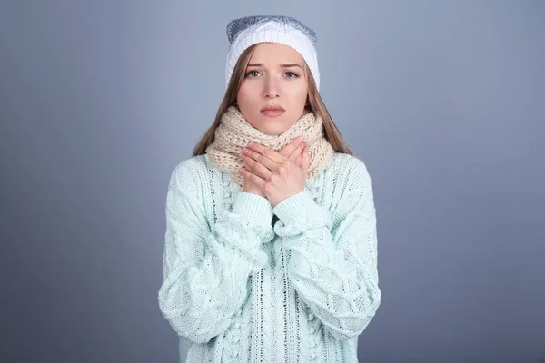 Больной молодой женщины, носящей теплый шарф на шее на цветном фоне — стоковое фото