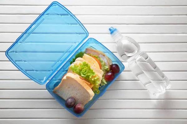 Lunchbox e bottiglia d'acqua su fondo di legno — Foto Stock