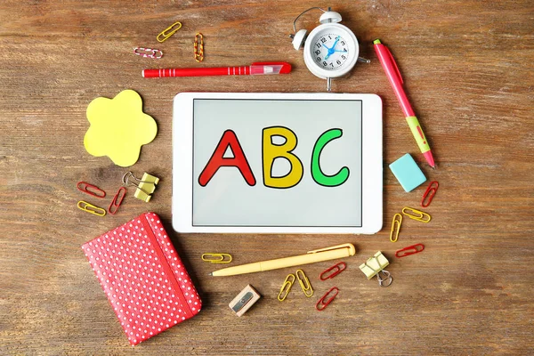 Tablet com mensagem ABC e artigos de papelaria sobre fundo de madeira — Fotografia de Stock