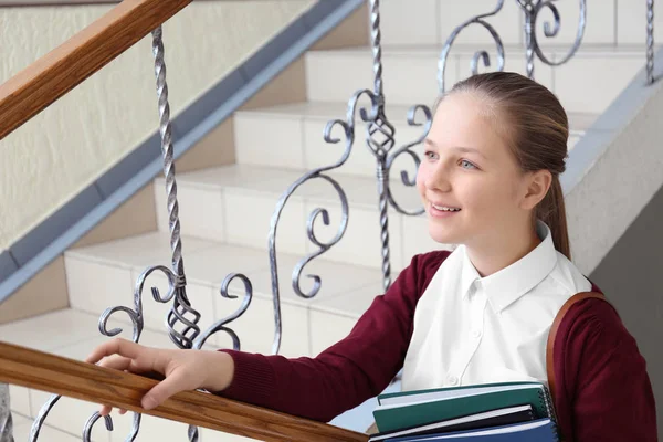 Милая девочка в школьной форме стоит на лестнице — стоковое фото