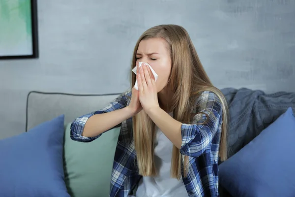 Νεαρή γυναίκα που φυσούν τη μύτη με χαρτομάντιλο στο σπίτι — Φωτογραφία Αρχείου