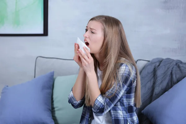 Young woman sneezing into tissue at home — Stock Photo, Image