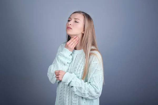 Zieke jonge vrouw met pijn in keel op kleur achtergrond — Stockfoto