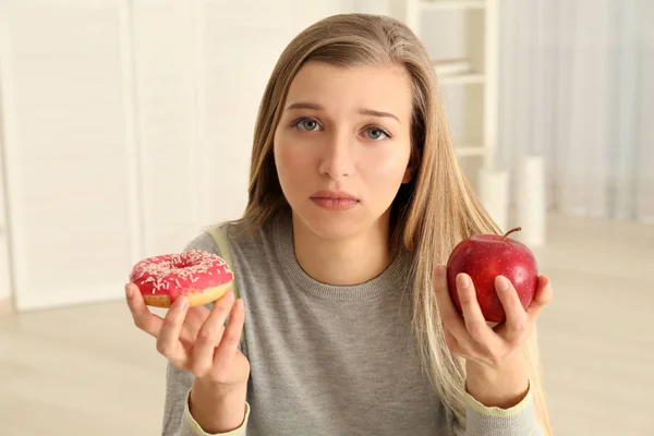 Belle jeune femme faisant le choix entre pomme et beignet — Photo