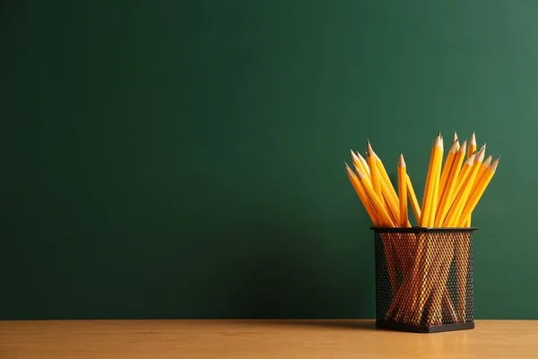 Pencils in metal holder on chalkboard background — Stock Photo, Image