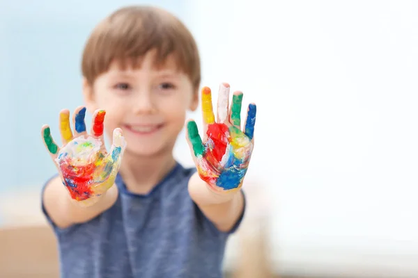 Carino bambino con le mani in vernice su sfondo sfocato — Foto Stock