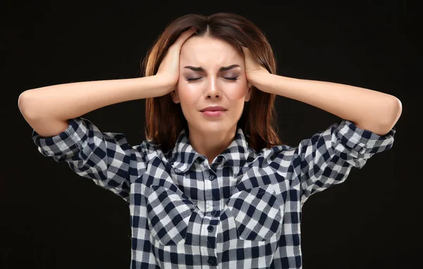 Schöne junge Frau mit Kopfschmerzen auf schwarzem Hintergrund — Stockfoto