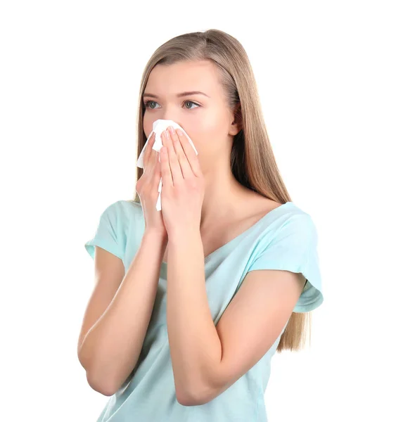 Young woman blowing nose on tissue against white background — Stock Photo, Image