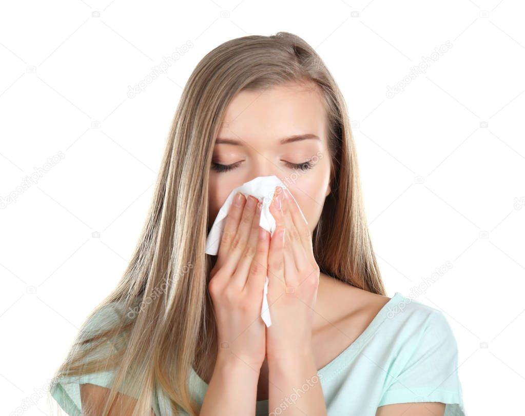 Young woman blowing nose on tissue against white background