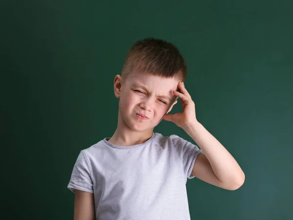 Kleiner Junge leidet unter Kopfschmerzen auf farbigem Hintergrund — Stockfoto