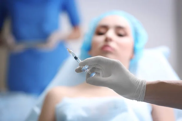 Plastischer Chirurg Hält Spritze Zur Gesichtsinjektion Mit Verschwommenem Patienten Hintergrund — Stockfoto