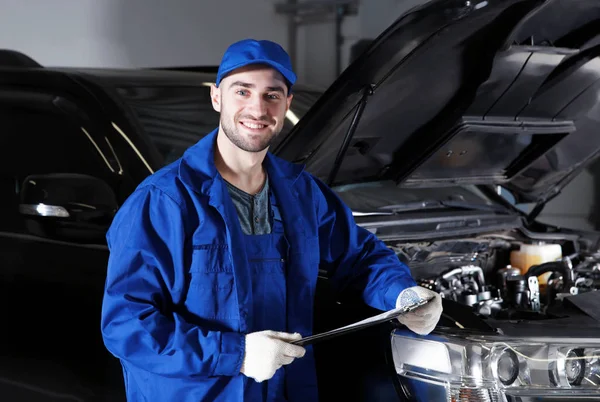 Mechanic in front of open car hood — Stock Photo, Image