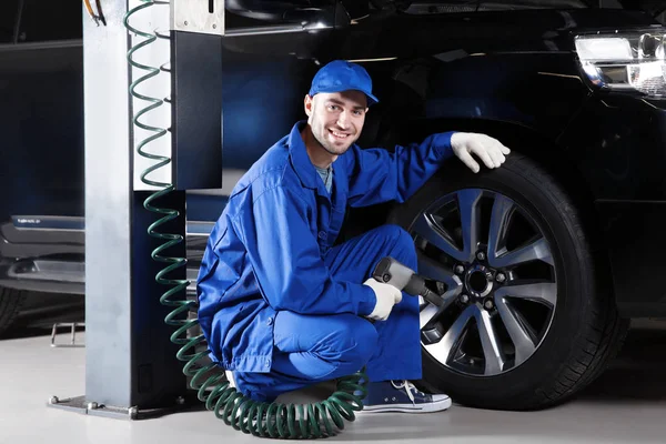 Young mechanic changing wheel — Stock Photo, Image