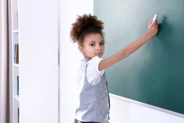 Portret van schoolmeisje schrijven op blackboard — Stockfoto