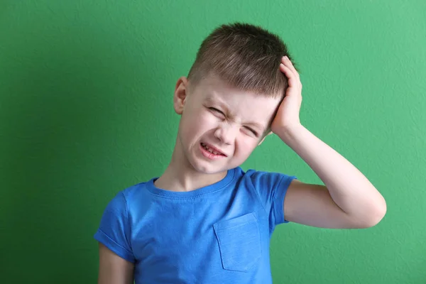 Niño que sufre de dolor de cabeza en el fondo de color — Foto de Stock