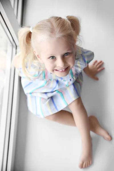 Little girl sitting on windowsill — Stock Photo, Image