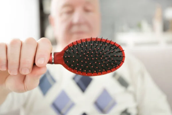 Hombre mayor sosteniendo cepillo de pelo, primer plano — Foto de Stock