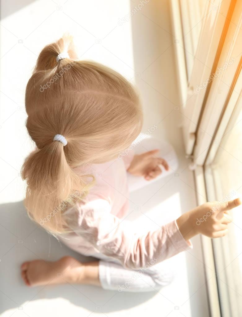 little girl sitting on windowsill