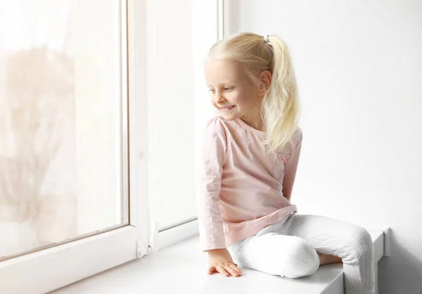 Kleines Mädchen sitzt auf Fensterbank — Stockfoto
