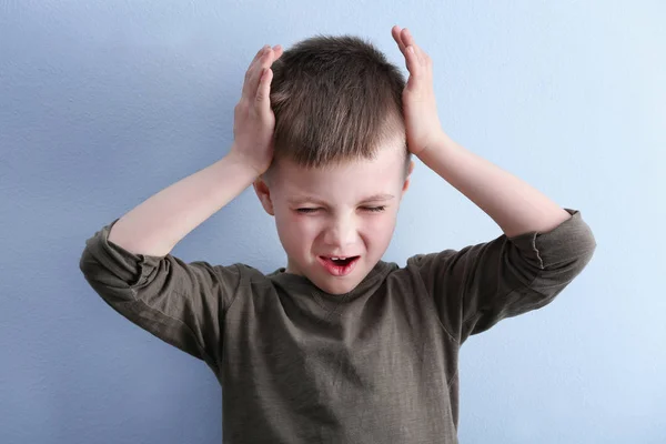 Niño que sufre de dolor de cabeza en el fondo de color —  Fotos de Stock