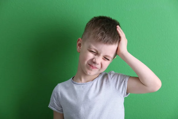 Kleiner Junge leidet unter Kopfschmerzen auf farbigem Hintergrund — Stockfoto