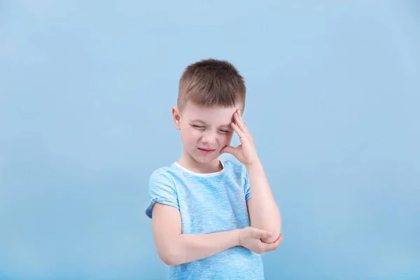 Kleiner Junge leidet unter Kopfschmerzen auf farbigem Hintergrund — Stockfoto