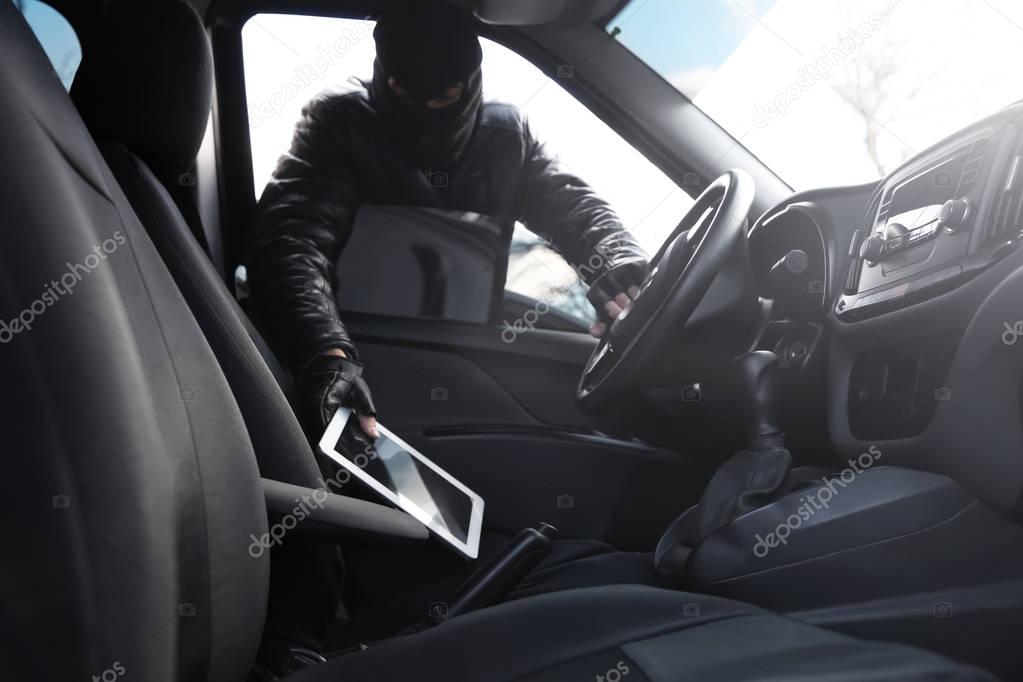 Thief stealing tablet from car