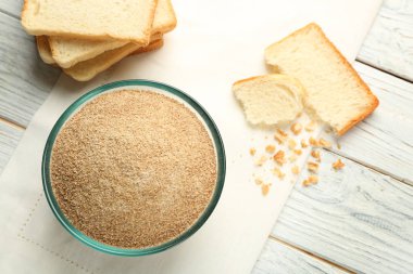 Small bowl of bread crumbs on wooden background clipart