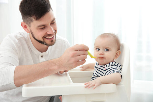 Father feeding cute baby daughter  