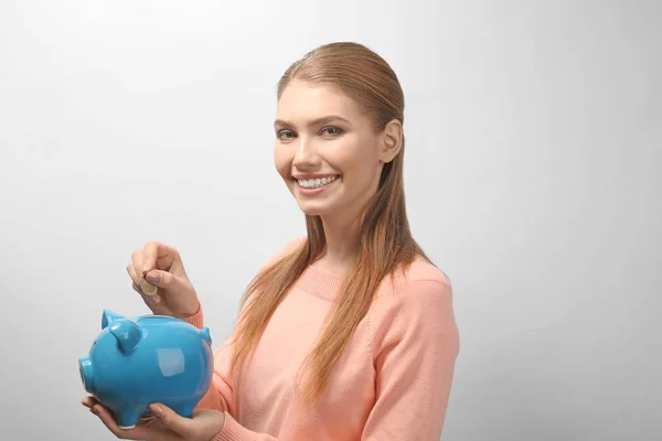 Mulher colocando moeda em banco porquinho — Fotografia de Stock