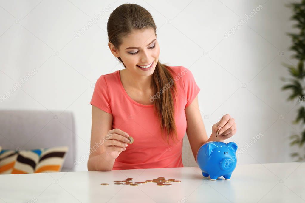 Beautiful young woman putting coins 