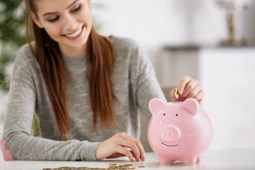 woman putting coins into piggy bank