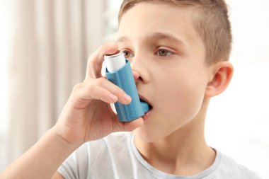 Boy using inhaler at home clipart