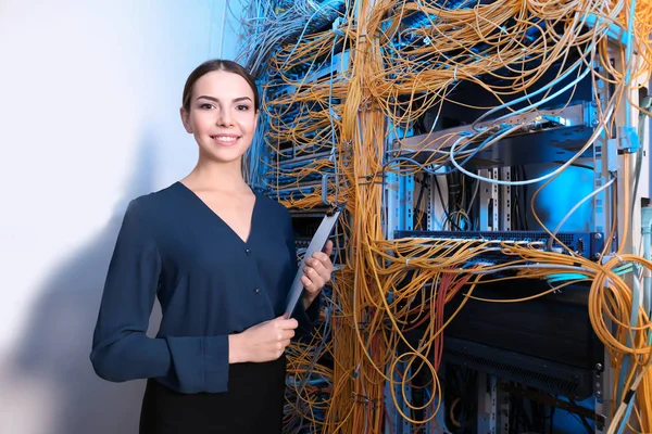 Mooie jonge ingenieur met Klembord in serverruimte — Stockfoto