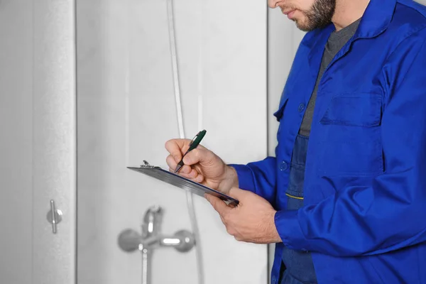 Fontanero de pie en el baño y la escritura en el portapapeles — Foto de Stock