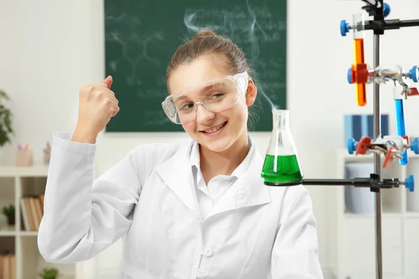 Entusiasmada menina da escola olhando para o frasco na aula de química — Fotografia de Stock