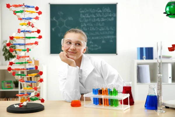 Beautiful school girl sitting at table in chemistry class — Stock Photo, Image
