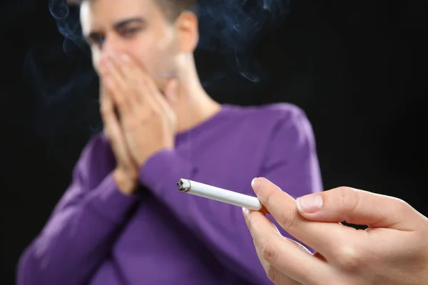 man covering face from cigarette smoke