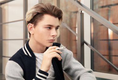 Merdivenlerde oturan ve sigara genç çocuk