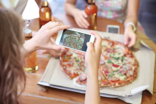 Woman taking photo of pizza