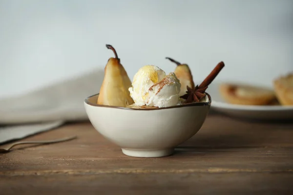 Kom met peren en ijs op de houten tafel — Stockfoto