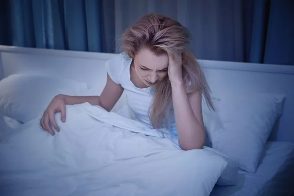 Wanita muda cantik menderita sakit kepala saat beristirahat di tempat tidur di malam hari — Stok Foto