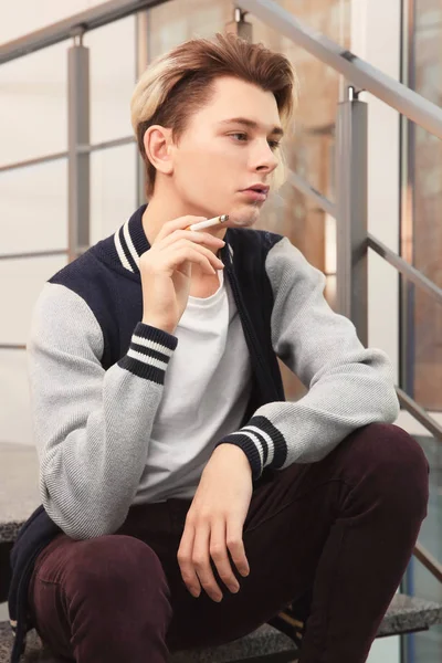 Teenage boy sitting on stairs and smoking — Stock Photo, Image