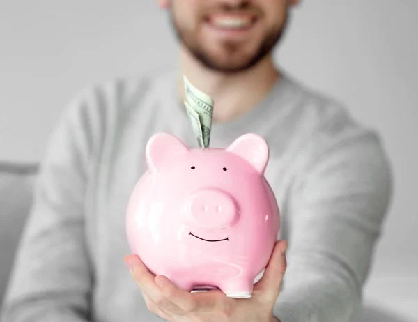 Mann hält Sparschwein mit Geld — Stockfoto