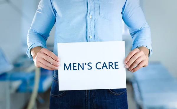 Man holding paper with text MEN'S CARE — Stock Photo, Image