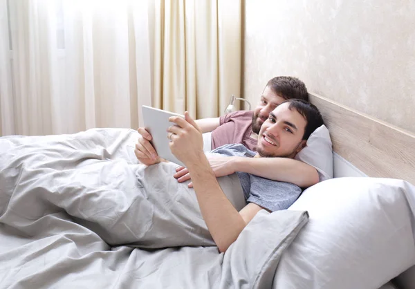 Homosexuální pár, ležící na posteli — Stock fotografie
